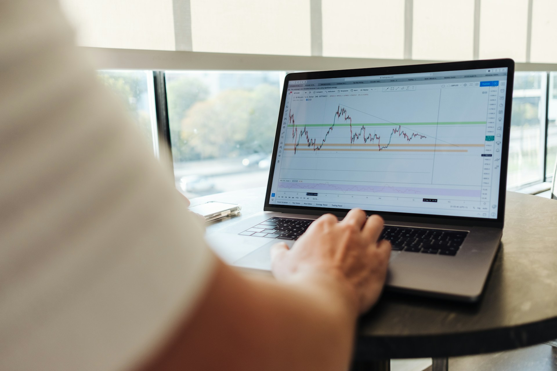 Automated Market Research With Search Scraping image Person analysing data and market trends on a laptop using a trading chart platform.